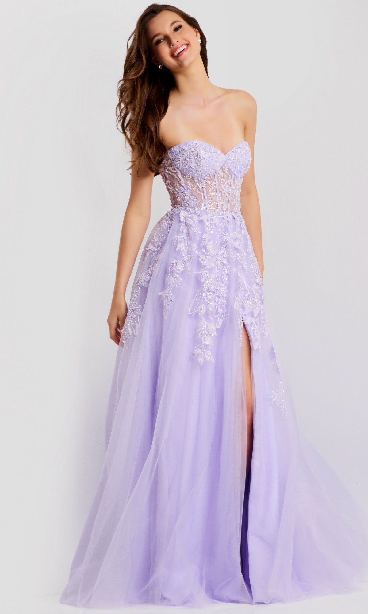 A woman poses against a neutral background in the Jovani 49656, a strapless long prom dress with a sweetheart neckline, delicate 3D floral appliques, tulle fabric, and a high slit.